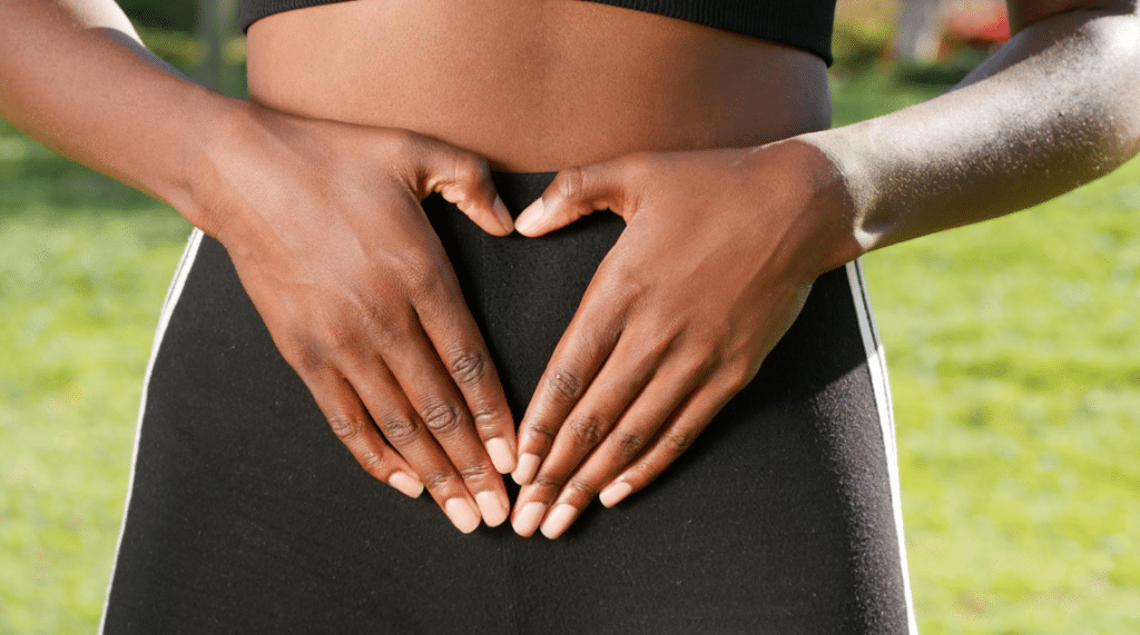 woman making a heart with her hands over her stomach