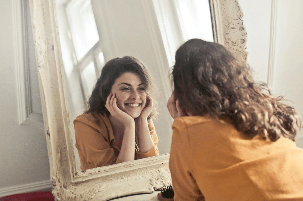 woman looking at herself in the mirror feeling happy after her ketamine therapy